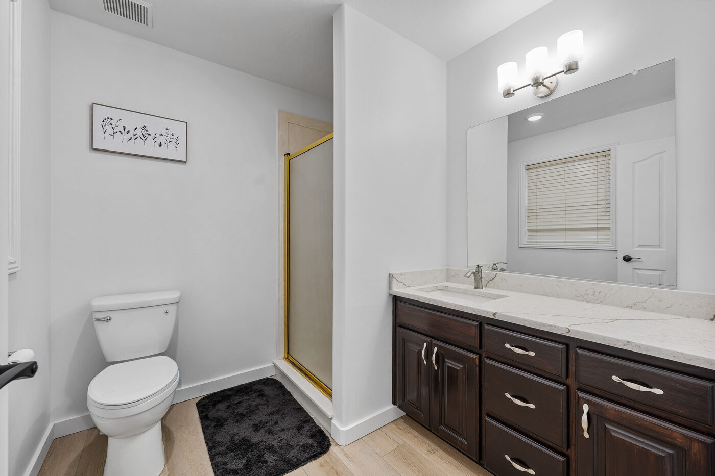 Updated master bathroom with dark wood vanity, quartz counter, and walk-in shower